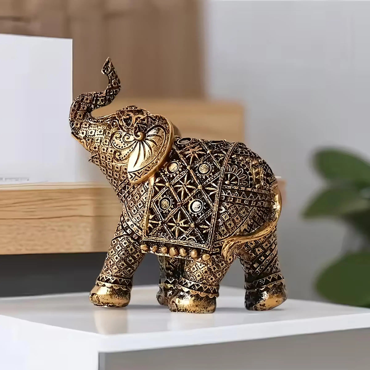 A vintage resin elephant ornament with intricate gold detailing, displayed on a white surface.