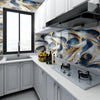 A kitchen featuring faux marble blue and gold patterned wall tiles, white cabinetry, and a stainless steel hood.
