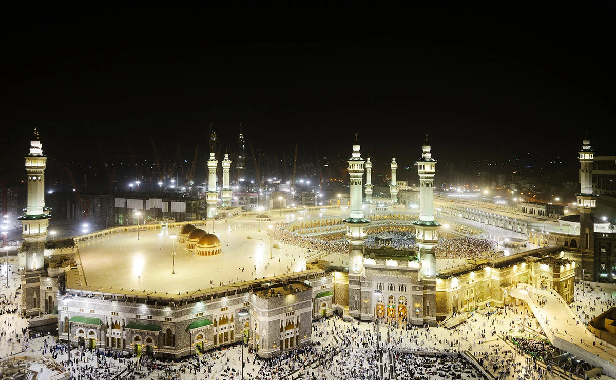 Night view of the Masjid an Nabawi in Mecca with crowds surrounding the Kaaba.