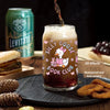 A glass of layered beverage decorated with silly goose book club stickers, next to a can and some food items.