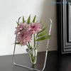 A clear acrylic frame vase holding pink dahlia flowers.