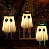 Three hanging ghost lights shaped like witches with pointed hats illuminate a dark outdoor scene.
