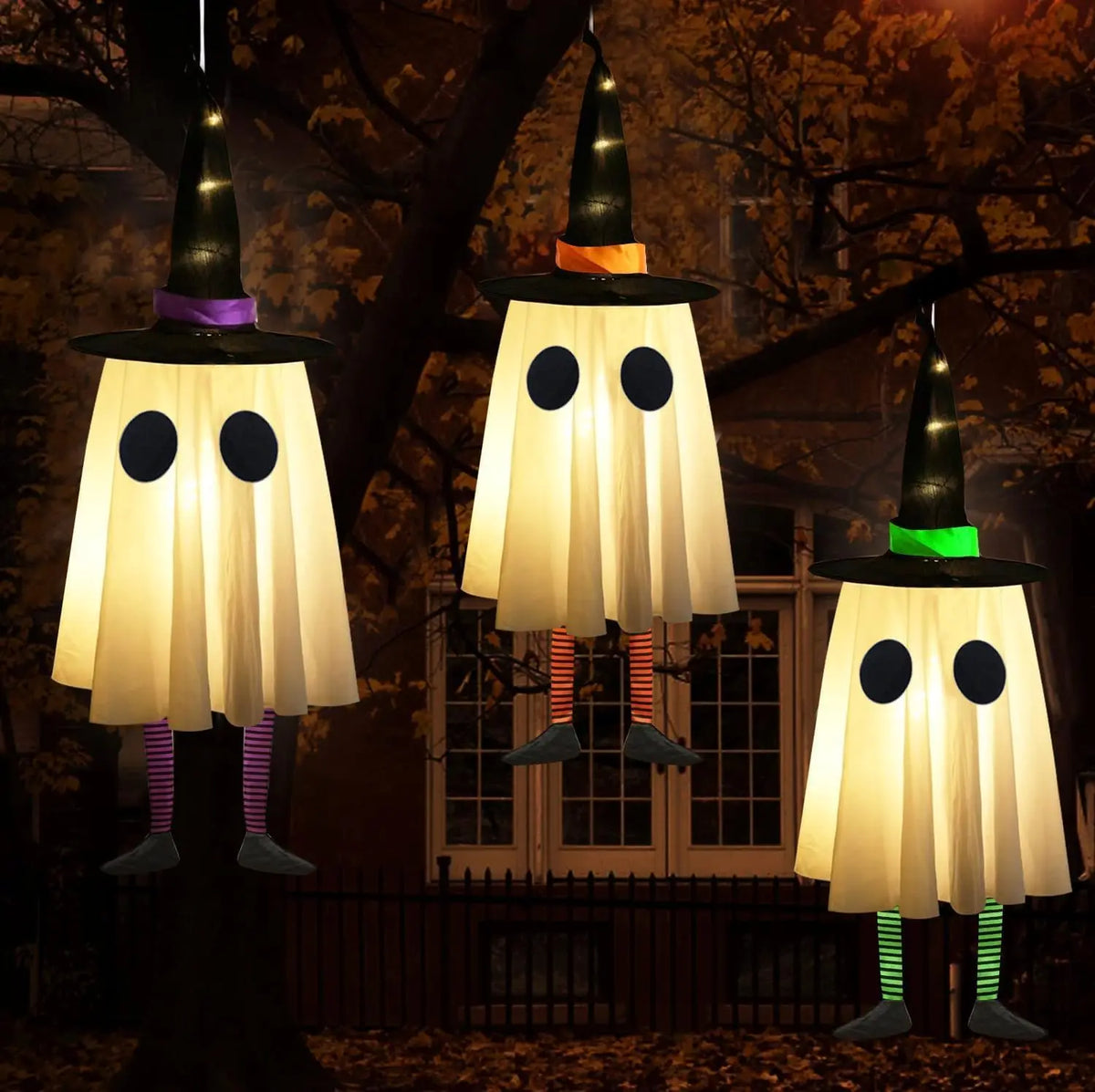 Three hanging ghost lights shaped like witches with pointed hats illuminate a dark outdoor scene.