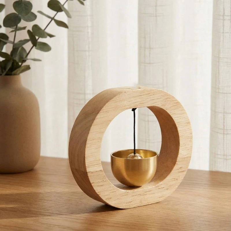A round wooden ring with a brass bowl inside, used as a magnetic wind chime doorbell.