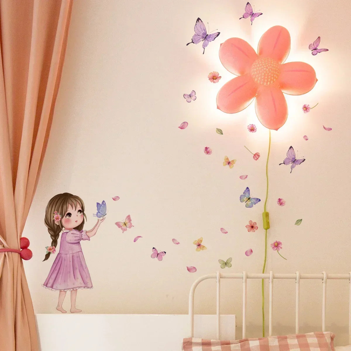 A young girl in a pink dress stands next to a crib decorated with butterfly wall stickers and light.