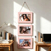 A set of three pink wooden photo frames displaying women's portraits mounted on a white wall.