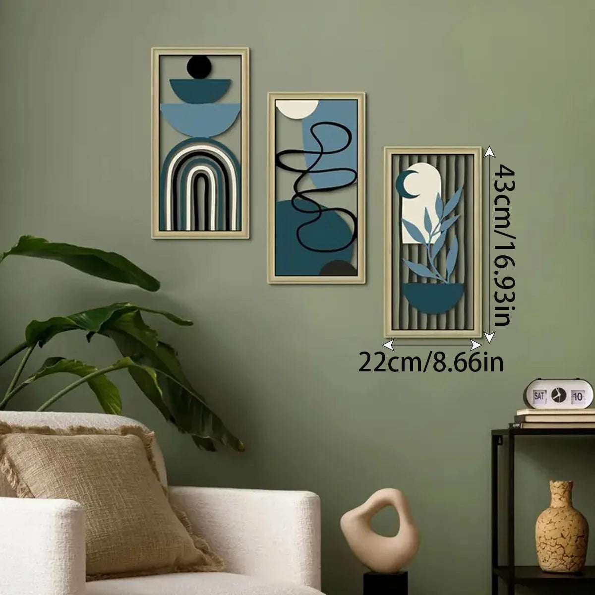 Drei gerahmte Holzdekorationsobjekte mit abstrakten blau-grauen geometrischen Formen an einer grünen Wand.