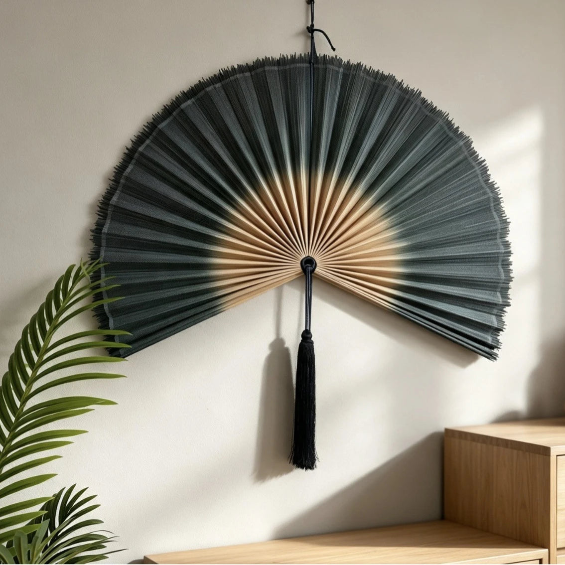 A handwoven bamboo wall fan decor with a dark gray and beige striped design mounted on a white wall.