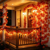 An autumn maple leaf vine garland with warm LED lights draped over a wooden porch railing.