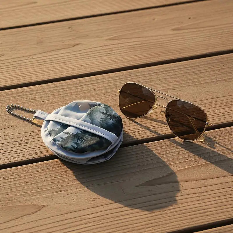 A pair of round sunglasses rests on a light blue and gray fabric item on a wooden surface.