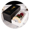 A black gift box containing an LED galaxy rose artificial flower with a glass dome, presented on a white surface.