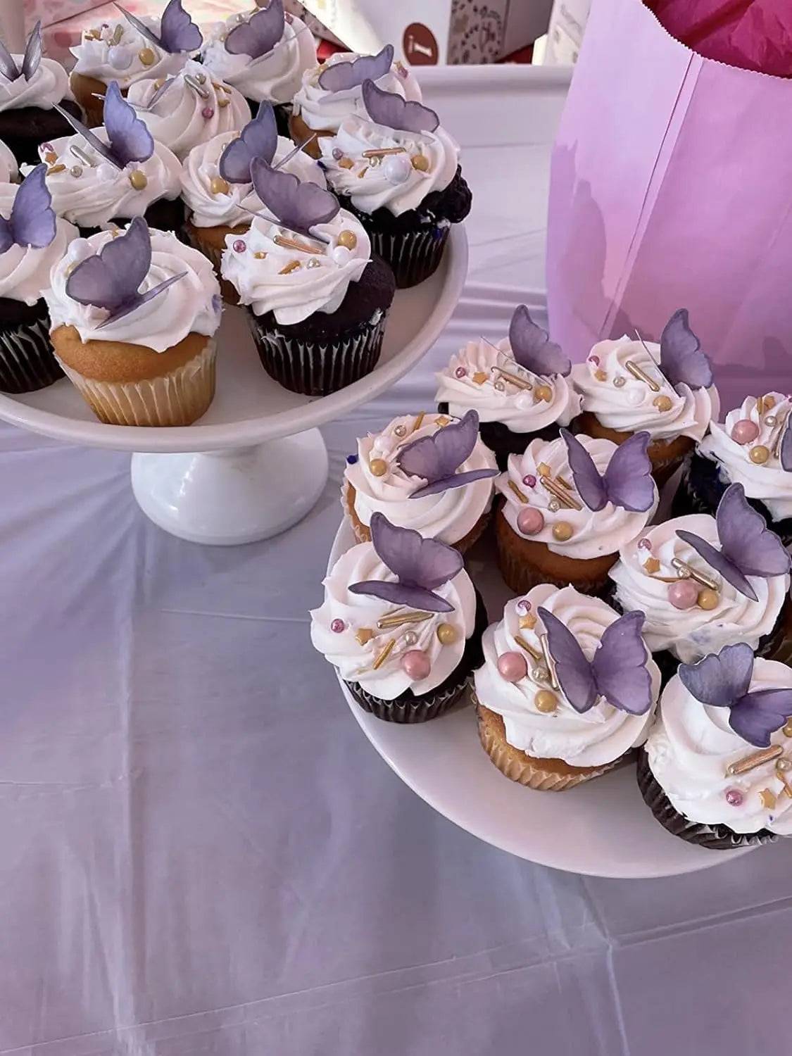 A display of purple and white butterfly decorated cupcakes on a white platter.
