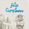 Blue script text saying Feliz Cumpleaños above a silver foil number balloon