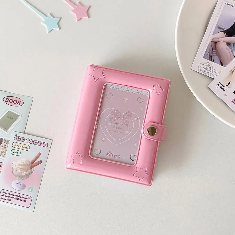 A pink compact star-shaped photo card holder album with a clear window and decorative elements is displayed on a white surfac