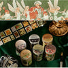 A collection of decorative washi tape rolls and a green fabric featuring winged figures.