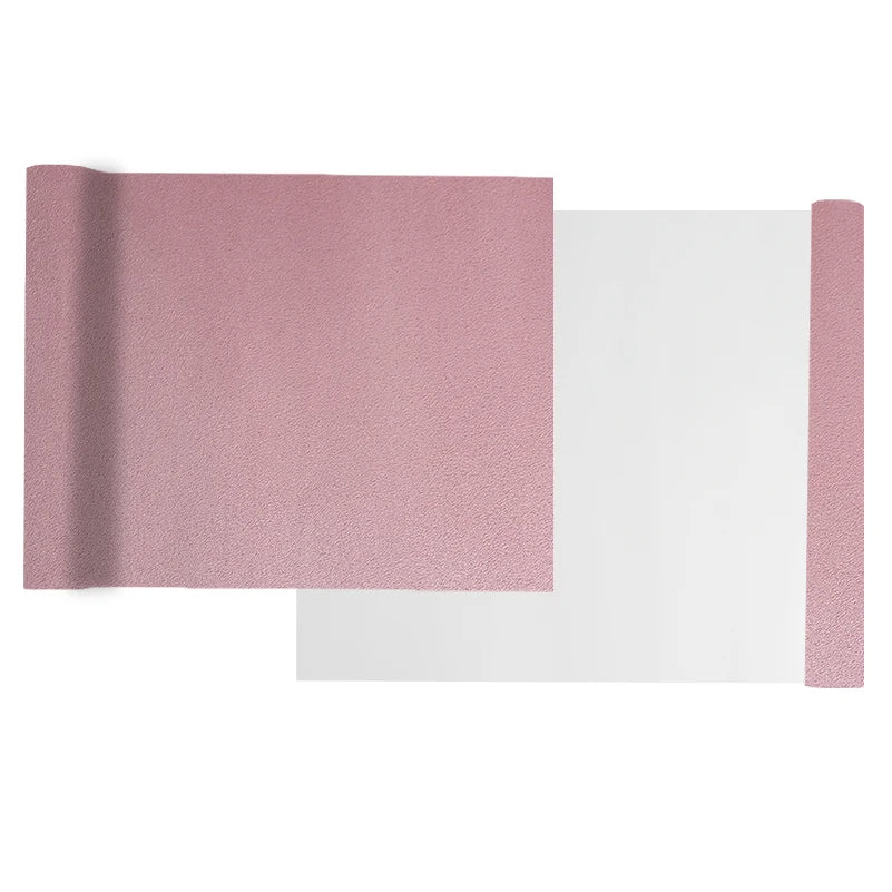 A roll of mauve suede wrap fabric with a white sheet visible next to it.