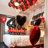 A balloon garland decoration featuring red and black balloons, including foil number balloons, set up for a birthday celebrat