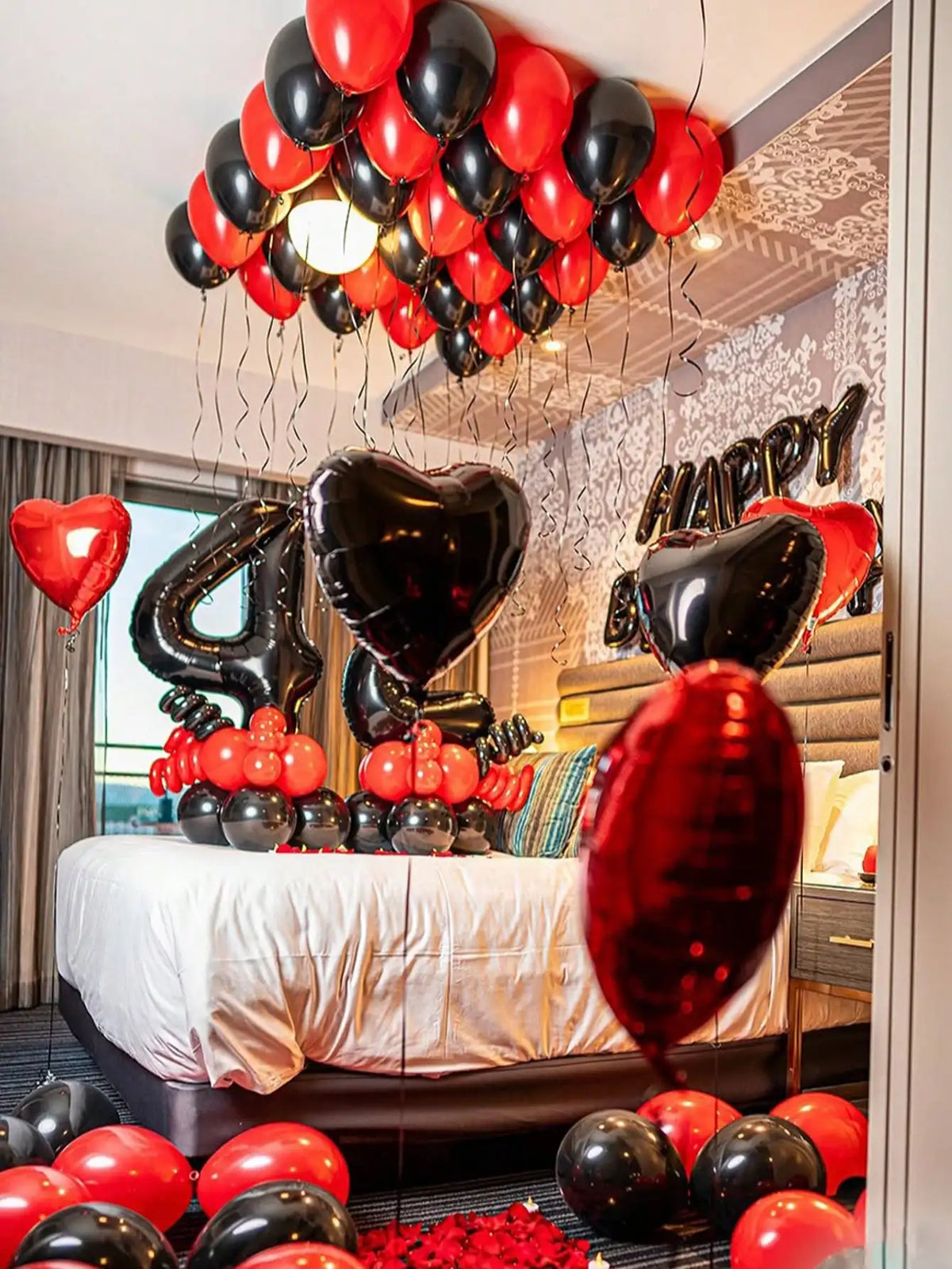 A balloon garland decoration featuring red and black balloons, including foil number balloons, set up for a birthday celebrat