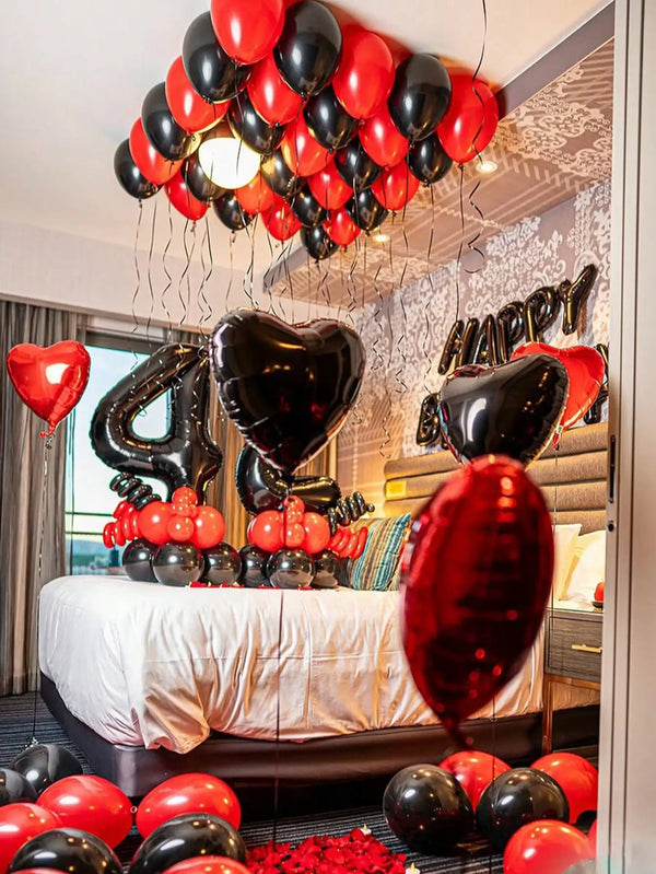 A balloon garland decoration featuring red and black balloons, including foil number balloons, set up for a birthday celebrat