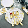 Elegant white and gold disposable dinnerware set with cutlery arranged on a gray surface.
