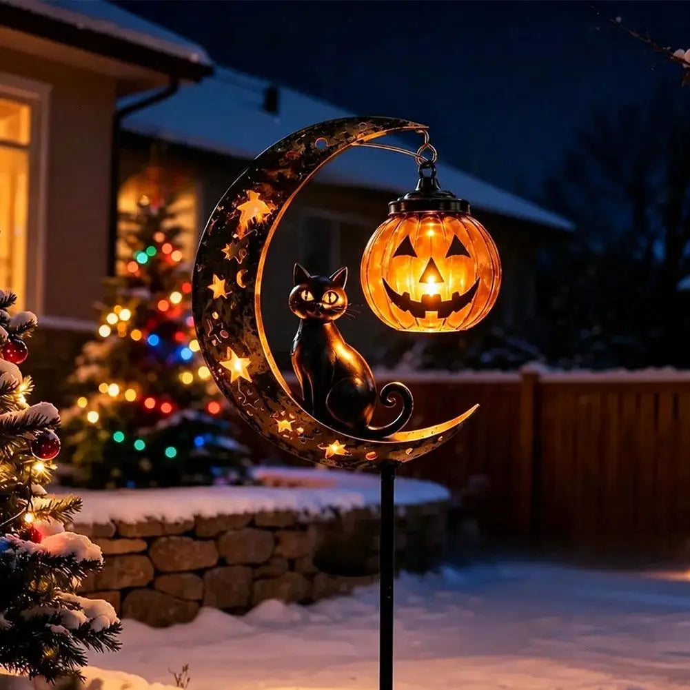 A Halloween stake light featuring a black cat silhouette and an orange pumpkin moon design illuminated in the dark garden.
