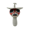 A plush toy featuring a stylized, grotesque face with red markings and a small, upward-pointing protrusion.