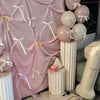 A display of pink and white bowknot ribbon cake toppers, including spherical decorations, arranged on a table.