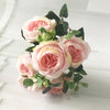 A bouquet of pink and cream silk rose and peony artificial flowers with green leaves.