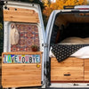 A vintage metal street sign decor is mounted on the side of a white van with wooden interior panels and a custom-built bed.