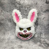 A white rabbit face mask with pink inner ears and glowing yellow eyes against a gray textured background.