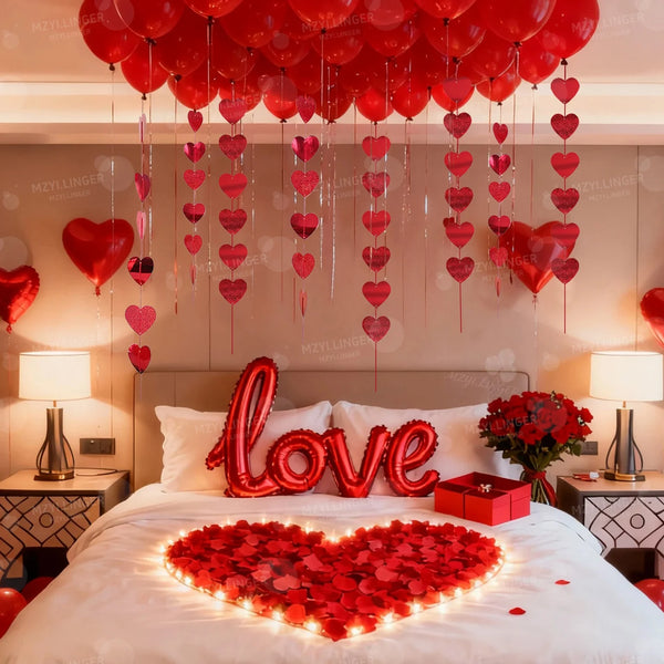 Schlafzimmer dekoriert mit roten Herzballons und einem herzförmigen Blumenarrangement auf dem Bett.