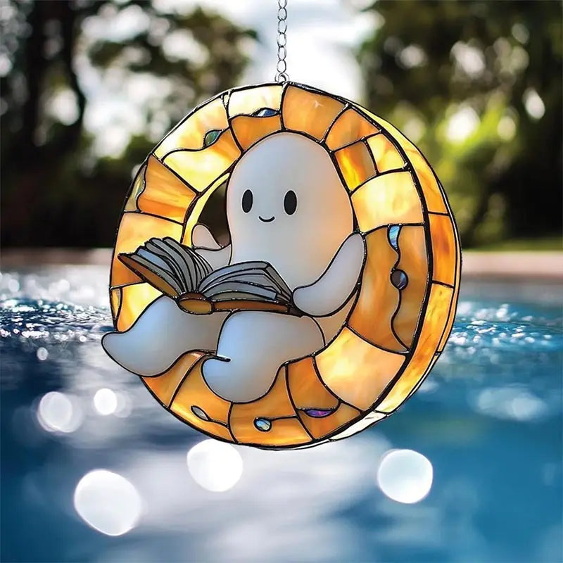 A hanging decoration shaped like a ghost reading an open book, made of stained glass.