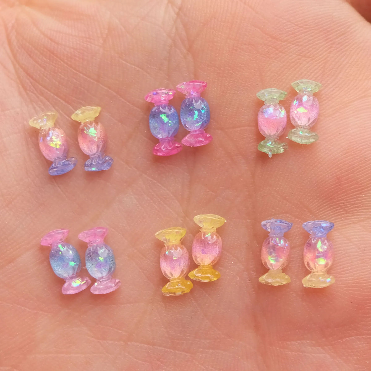 Una mano sostiene varios adornos de uñas en forma de tortuga mini de colores, en tonos rosa, púrpura y verde.