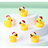 A display of glow-in-the-dark Christmas duck figurines wearing Santa hats on white cake stands.