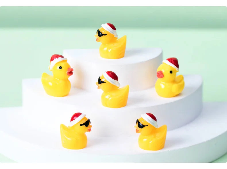 A display of glow-in-the-dark Christmas duck figurines wearing Santa hats on white cake stands.