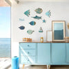 A display of ten wooden hanging fish decorations on a white wall above a light blue cabinet.