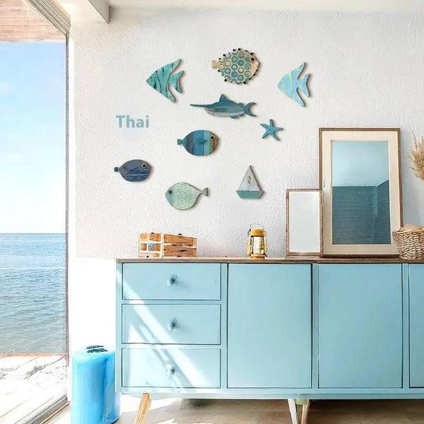 A display of ten wooden hanging fish decorations on a white wall above a light blue cabinet.