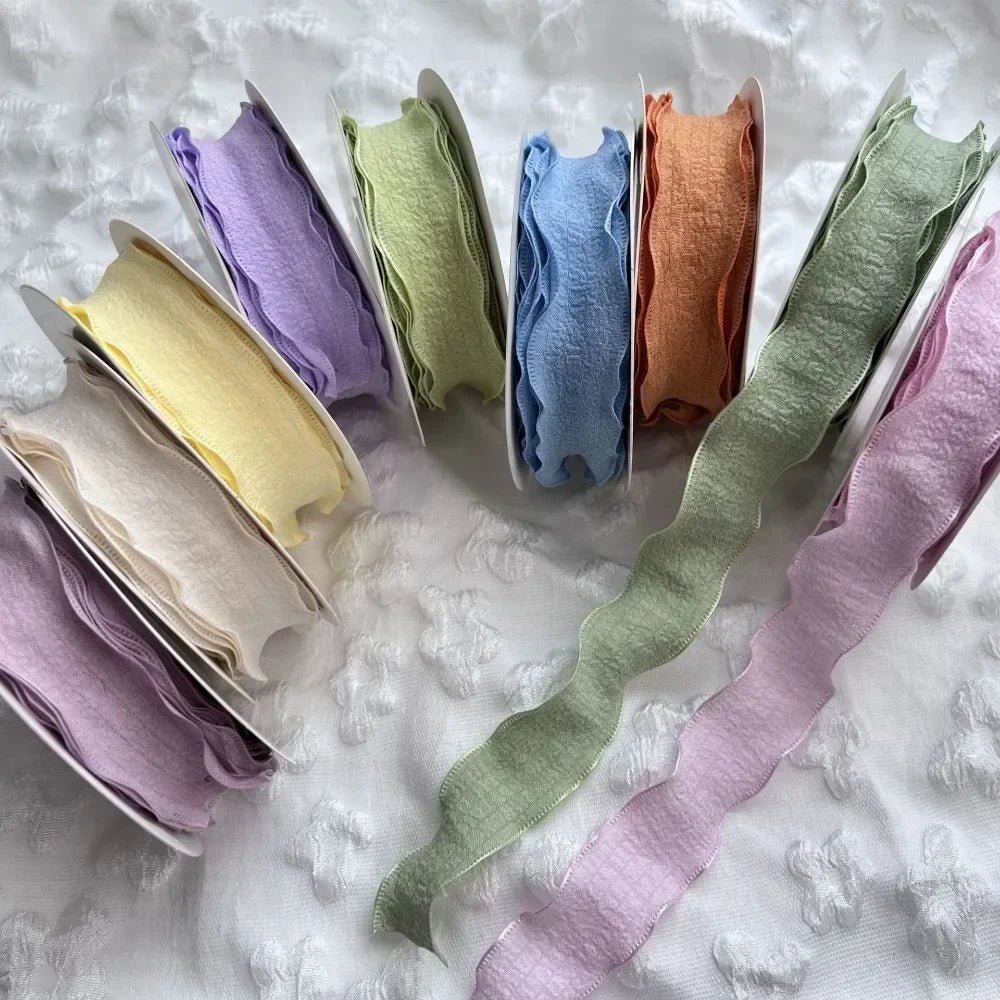 A collection of 10 yards of decorative fishtail yarn ribbon in various pastel shades including lavender, mint green, yellow, 