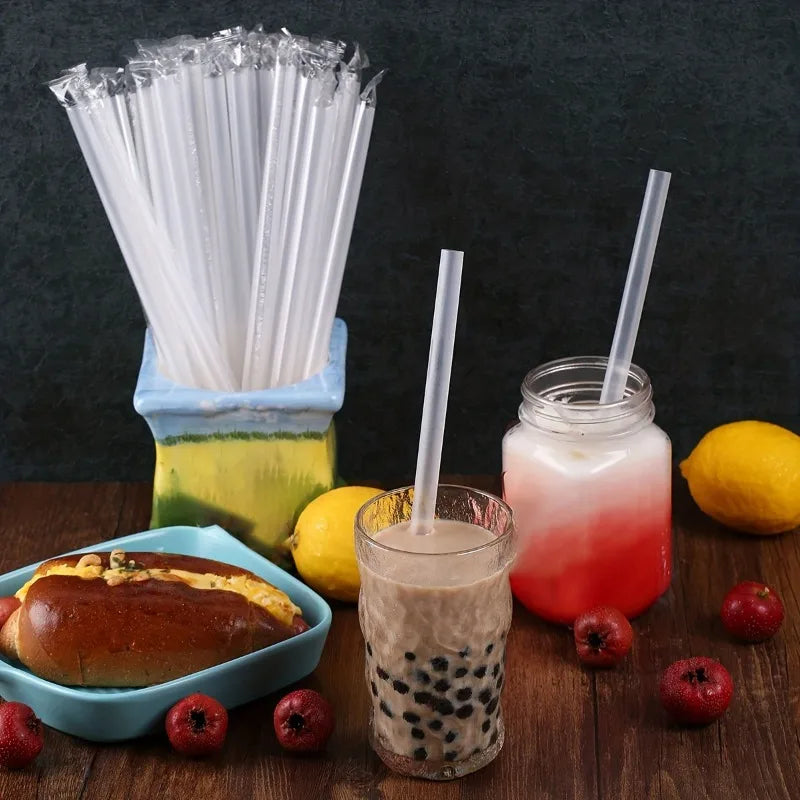 A glass jar filled with a pink and red beverage sits next to a glass of iced coffee with a straw, surrounded by disposable dr
