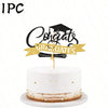 A white cake with gold accents and a black graduation topper featuring the words Congrats Graduates