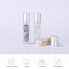 A set of ten clear glass roll-on bottles with silver caps containing semi-precious stone roller balls and an amber oil.