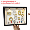 Schwarze Displaybox mit zehn Mini-Fotoframes, acht zufälligen Figuren und Lichtern.