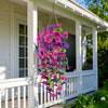 Purple and magenta artificial morning glory flowers hanging in a white porch window