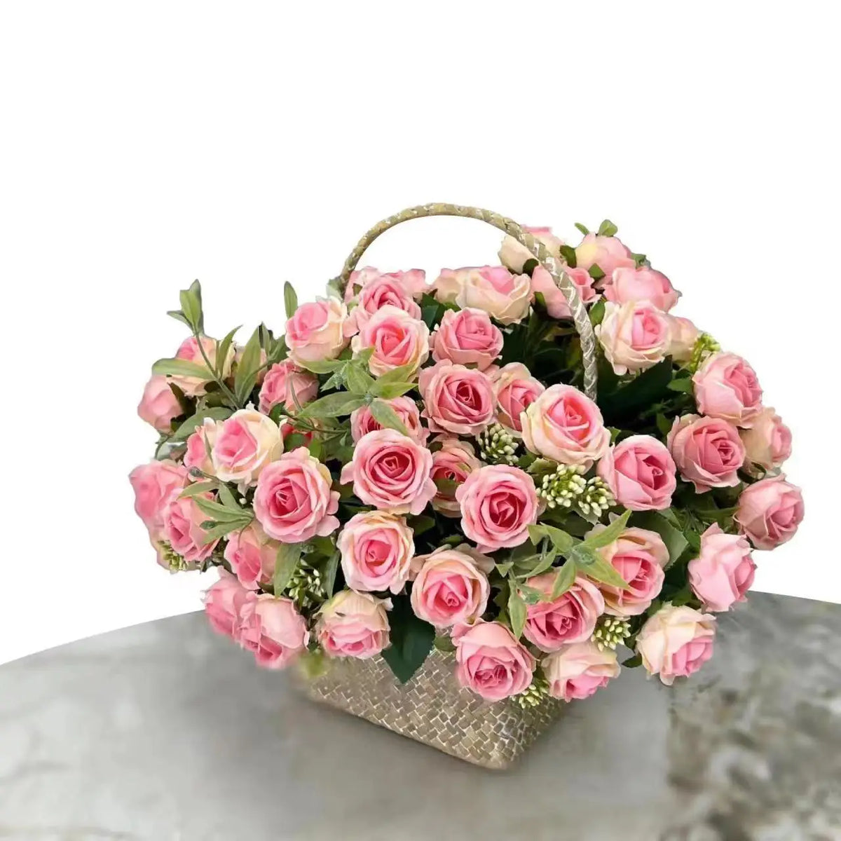 A bouquet of pink and blush artificial roses in a woven basket