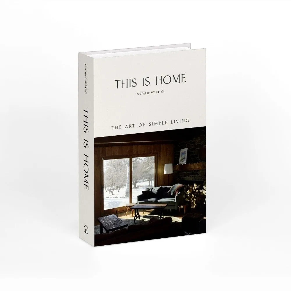 A white book titled This Is Home by Natalie Walton is displayed against a dark wooden background.