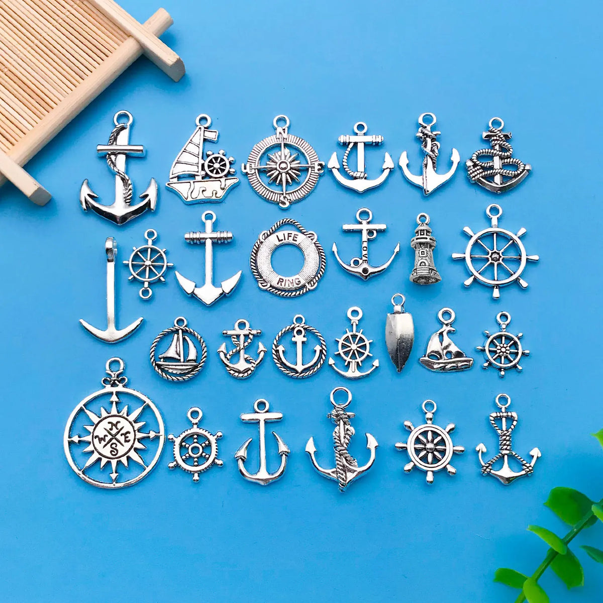 A collection of vintage ship anchor charms and nautical jewelry components arranged on a blue background.