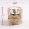A natural wooden candle holder wrapped with twine features a heart-shaped wooden tag and white floral decorations.