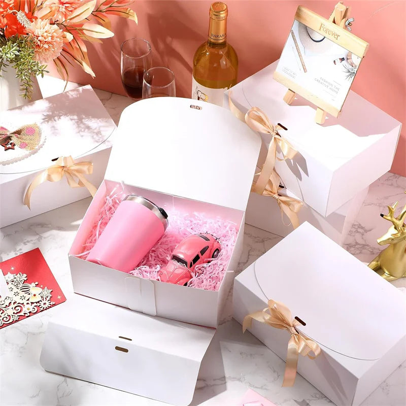 White gift box with pink items and gold ribbon ties displayed on a marble surface.
