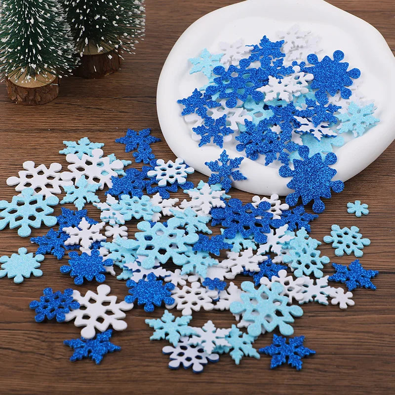 Collection de flocons de neige en mousse autocollants bleu et blanc dispersés sur une surface en bois avec un contenant blanc