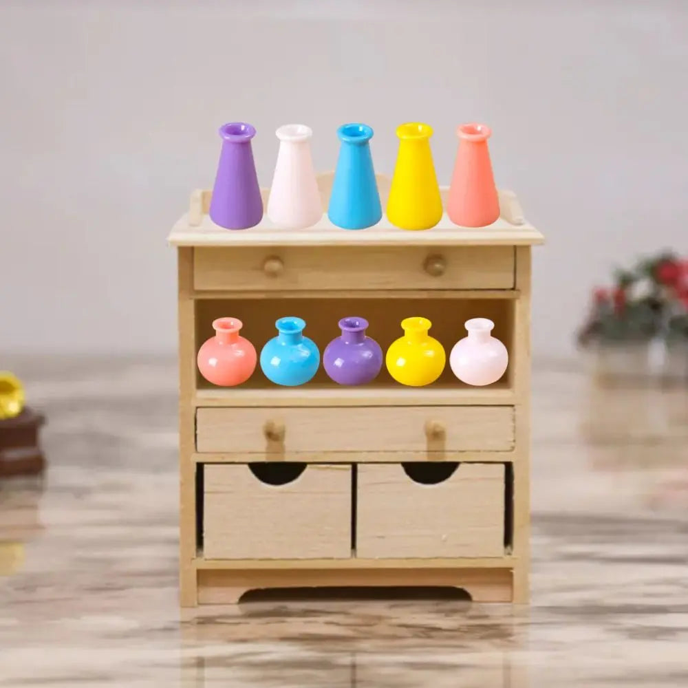 A wooden storage box holds ten miniature resin vases in various bright colors like purple, pink, blue, and yellow.